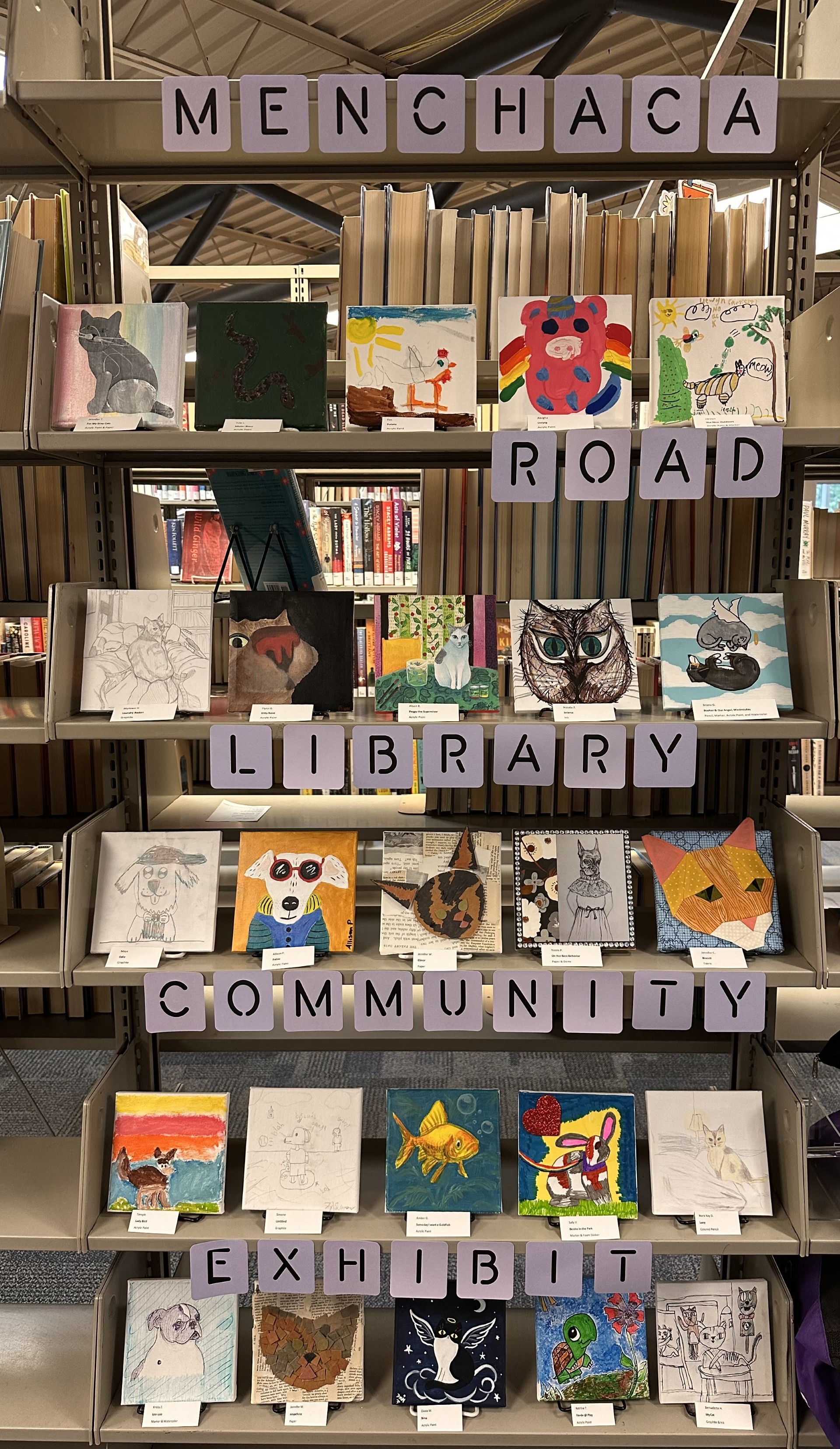 Five book shelves with 4 inch by 4 inch paintings and collaged art of community member's pets. The words Menchaca Road Library community exhibit run across the bottom of the book shelves