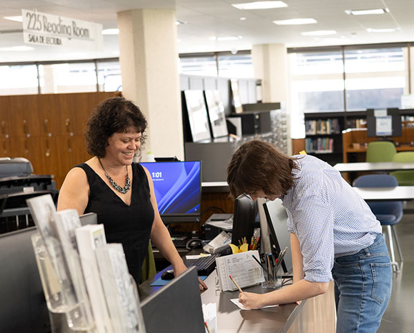 staff helping someone at the desk in the reading room