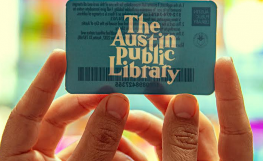 Hands holding up an Austin Public Library card 