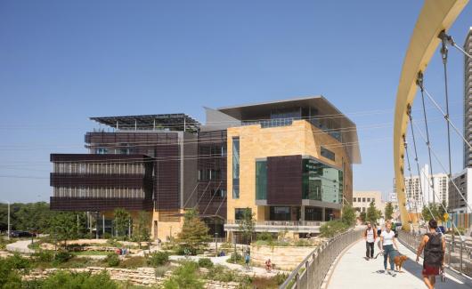 Austin Central Library exterior, viewed from bridge with people and dog walking by