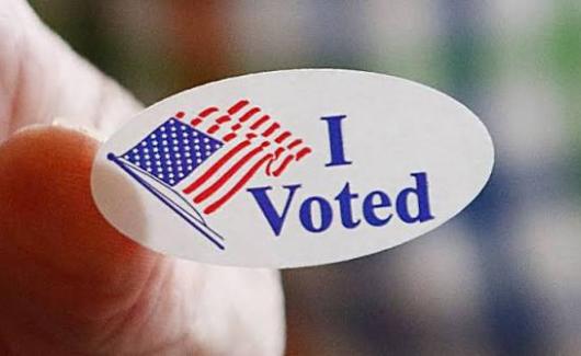 Hand holding an "I Voted" sticker from a polling location 
