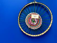 A wheel threaded with yarn, with colorful yarn strands interwoven in a spiral pattern at the center