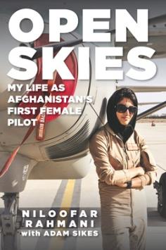 Woman in flightsuit leaning against airplane