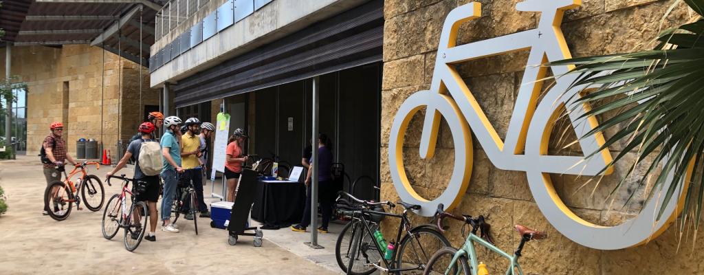 bikers lined up outside the Austin Public Library by a giant Bicycle sign