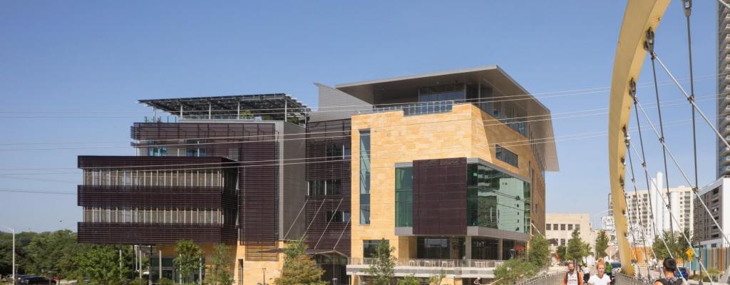 Austin Central Library exterior, viewed from bridge with people and dog walking by