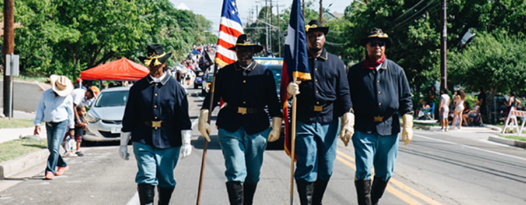 4 men in uniform marching with flags