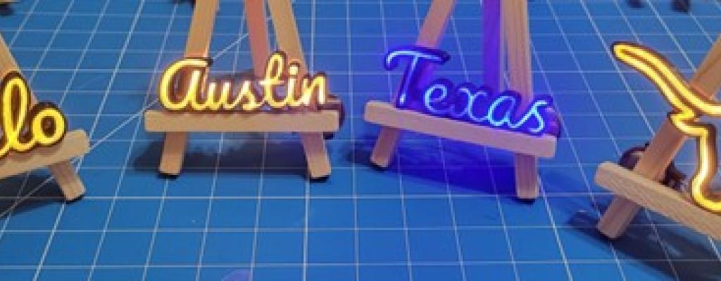 Small neon lights that spell out hello, Austin, Texas, and image of a Longhornon easels